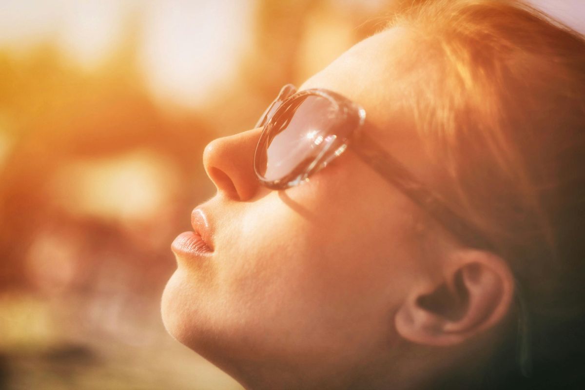 A woman staring at the sun after applying methylene blue sunscreen