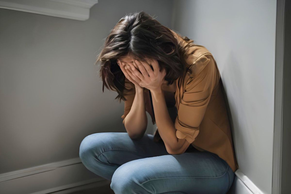 A woman sitting on the floor with her hands covering her face
